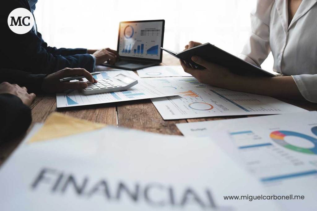 Grupo de personas trabajando en análisis financiero con gráficos y documentos sobre una mesa de madera.
