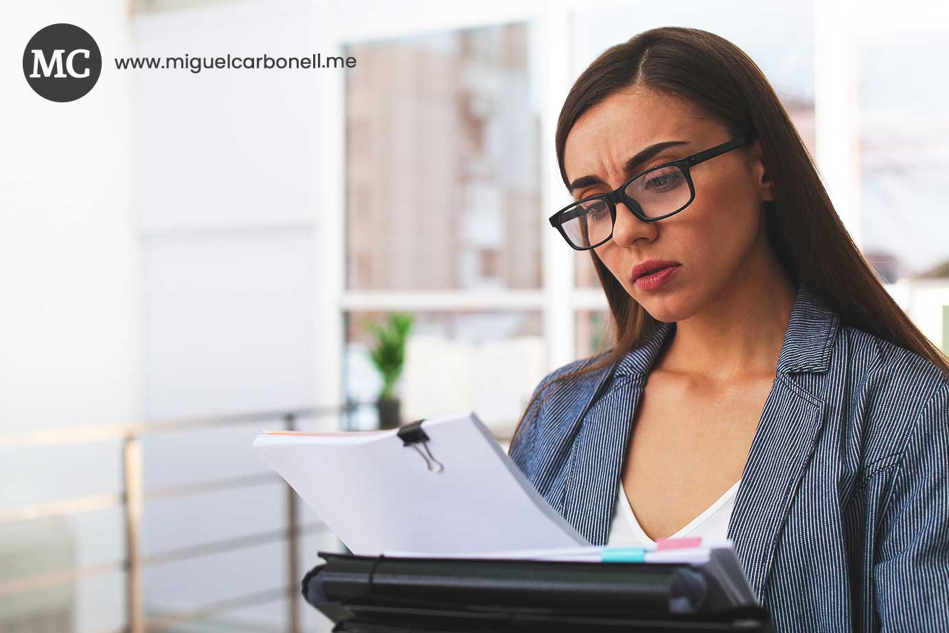 Mujer con gafas leyendo documentos en un entorno de oficina